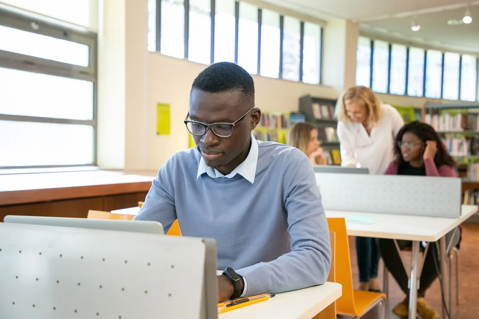 Étudiant concentré devant son ordinateur dans une bibliothèque universitaire
